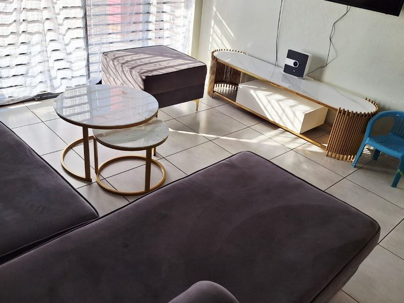 A living room area featuring light-colored floor tiles and a large sliding glass door providing natural light.