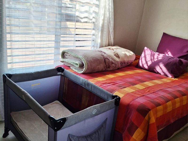 A bedroom featuring tiled flooring and horizontal window blinds, providing a functional space with natural light.
