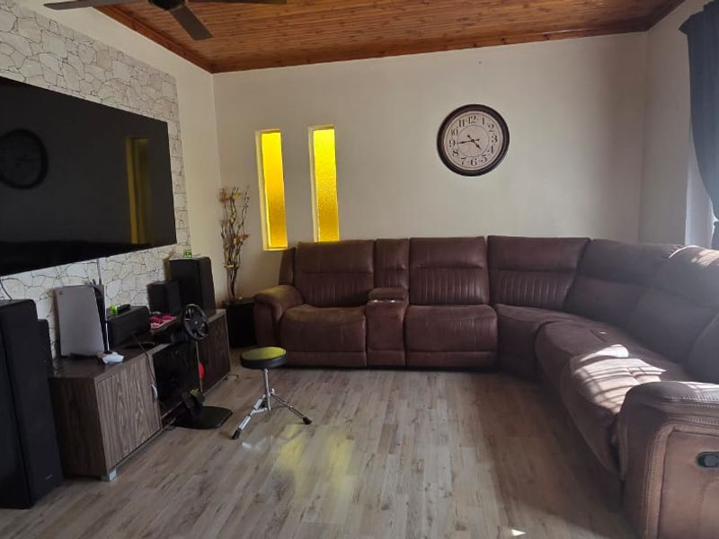 A living room featuring a timber ceiling, laminate flooring, and a stone feature wall with vertical accent windows.