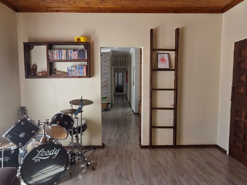 Living room featuring laminate flooring, timber ceiling accents, and a solid timber door, providing access to the hallway.
