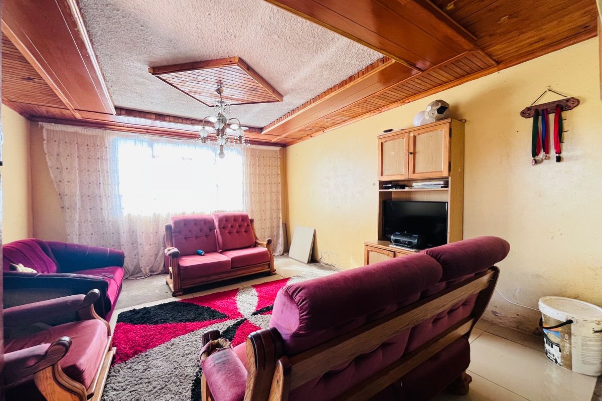 Living room featuring timber ceiling paneling, tiled flooring, and built-in cabinetry, requiring cosmetic updates to the wall finishes.