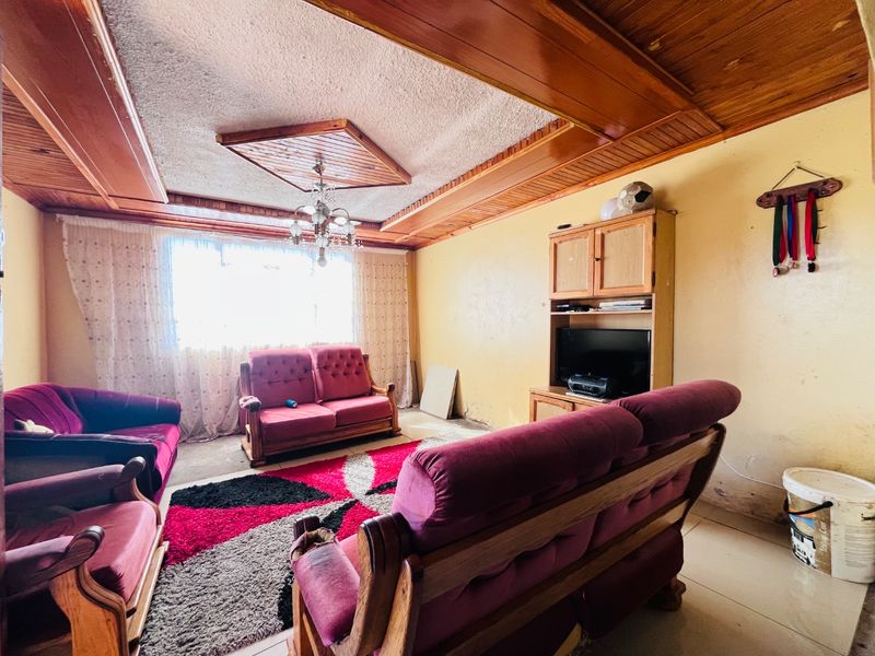 Living room featuring timber ceiling paneling, tiled flooring, and built-in cabinetry, requiring cosmetic updates to the wall finishes.