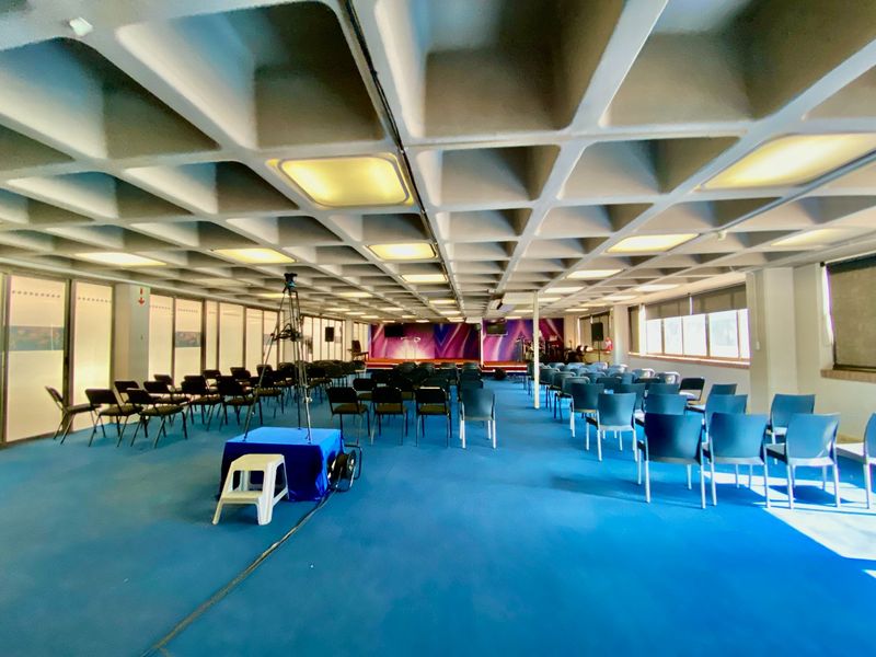 A large commercial multi-purpose hall featuring a distinctive waffle slab ceiling, recessed lighting, and expansive windows, suitable for events or meetings.