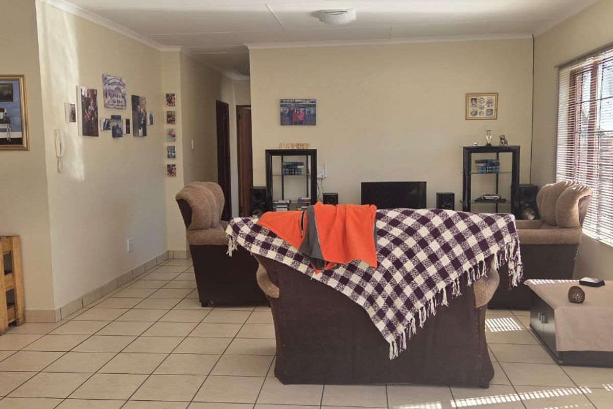 A spacious living area featuring neutral tiled flooring and large sliding glass doors with venetian blinds, providing natural light and access to the exterior.