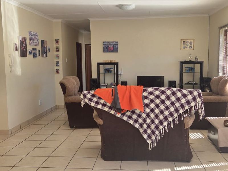 A spacious living area featuring neutral tiled flooring and large sliding glass doors with venetian blinds, providing natural light and access to the exterior.
