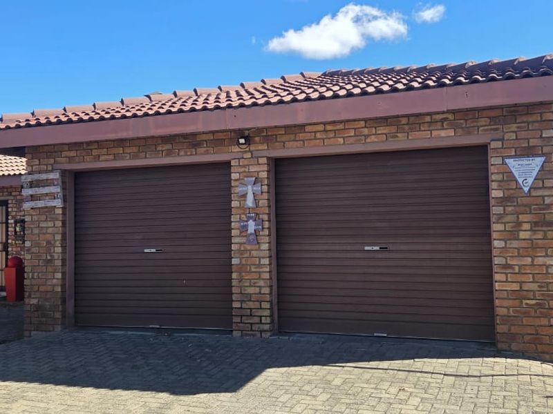 A well-maintained double garage with face brick facade, tiled roof, and paved driveway access.