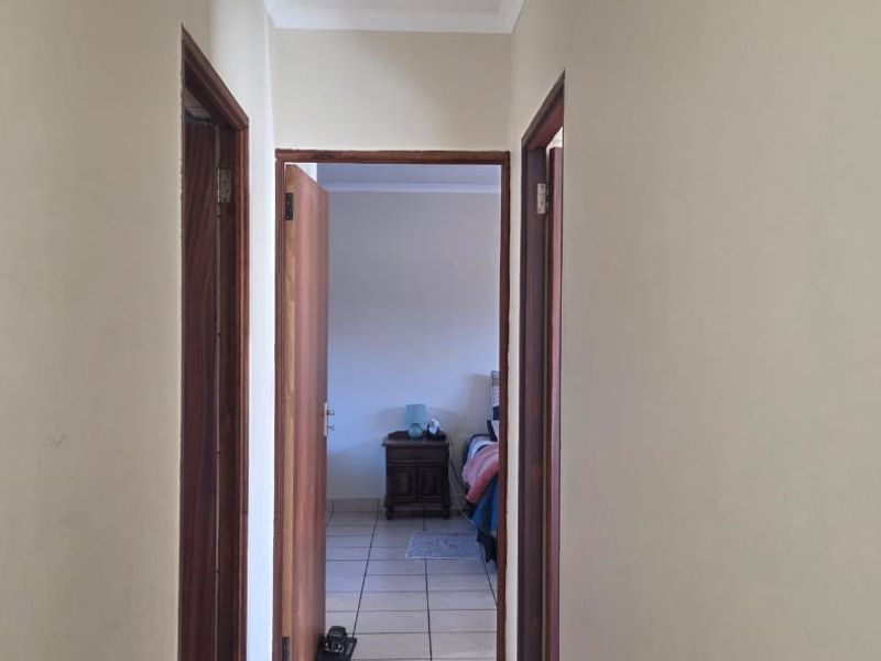 A simple interior hallway connecting rooms, featuring neutral walls and wooden door frames.
