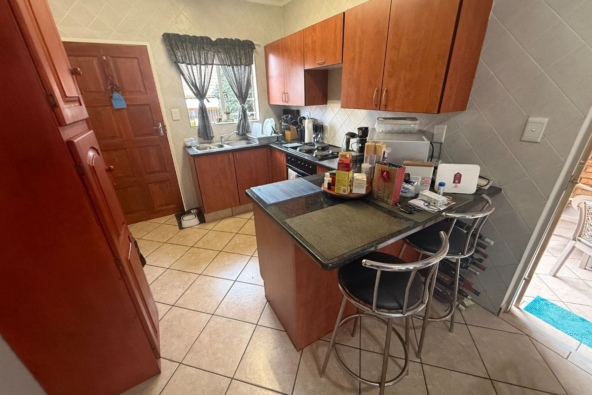 A functional kitchen featuring wooden cabinetry, granite countertops, a tiled backsplash, and a breakfast nook area with direct access to the exterior.