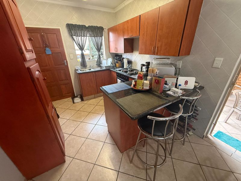 A functional kitchen featuring wooden cabinetry, granite countertops, a tiled backsplash, and a breakfast nook area with direct access to the exterior.