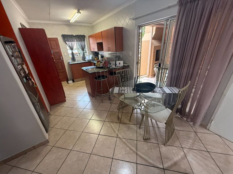 Open-plan kitchen and dining area featuring tiled flooring, built-in cabinetry, and direct access to an outdoor patio through sliding glass doors.