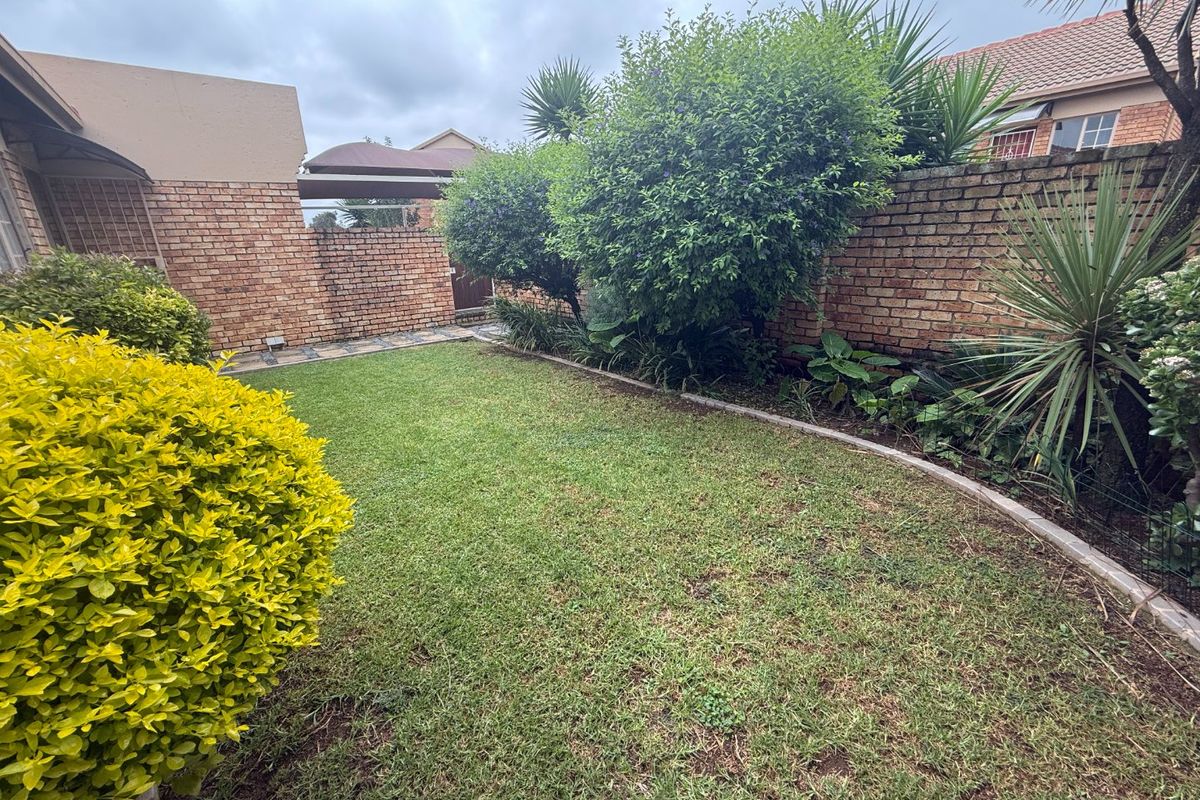 A private rear garden featuring a well-maintained lawn and established perimeter brick boundary walls.