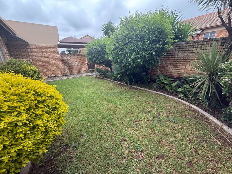 A private rear garden featuring a well-maintained lawn and established perimeter brick boundary walls.