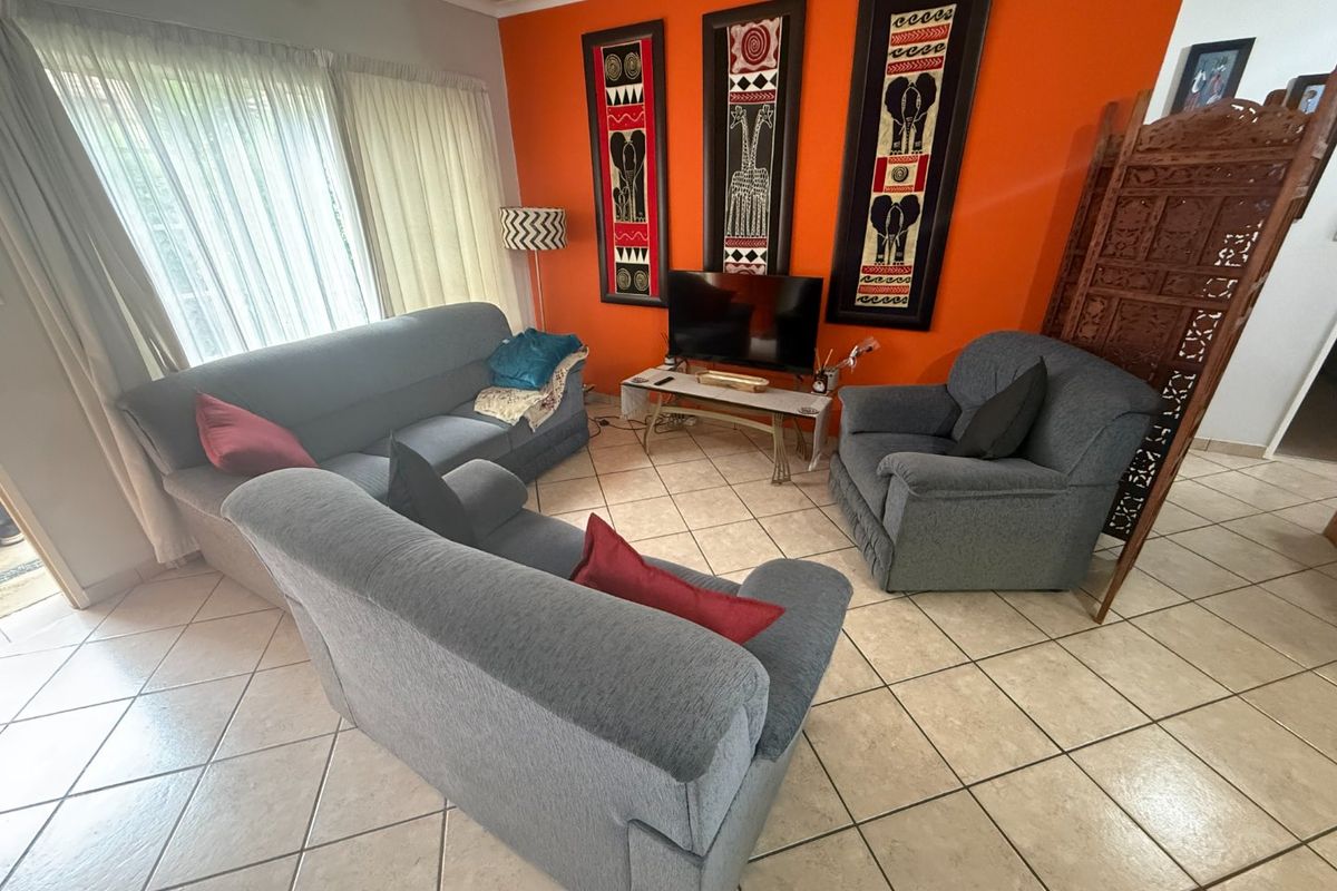 A living room featuring ceramic floor tiles and a large sliding glass door providing natural light.