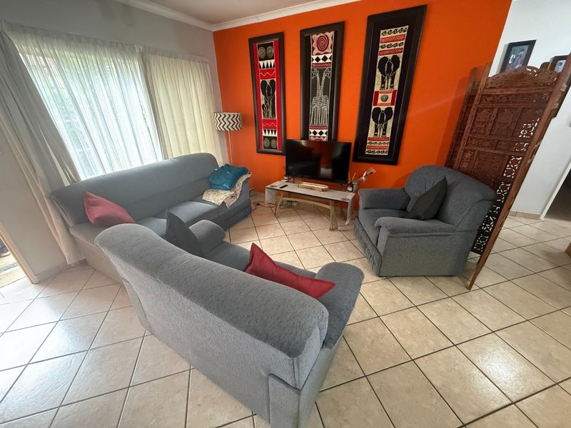 A living room featuring ceramic floor tiles and a large sliding glass door providing natural light.