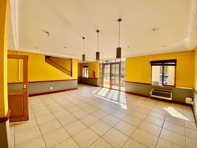 Spacious commercial entry area featuring tiled flooring, pendant lighting, an integrated air conditioning unit, and a secure entrance with a metal gate.
