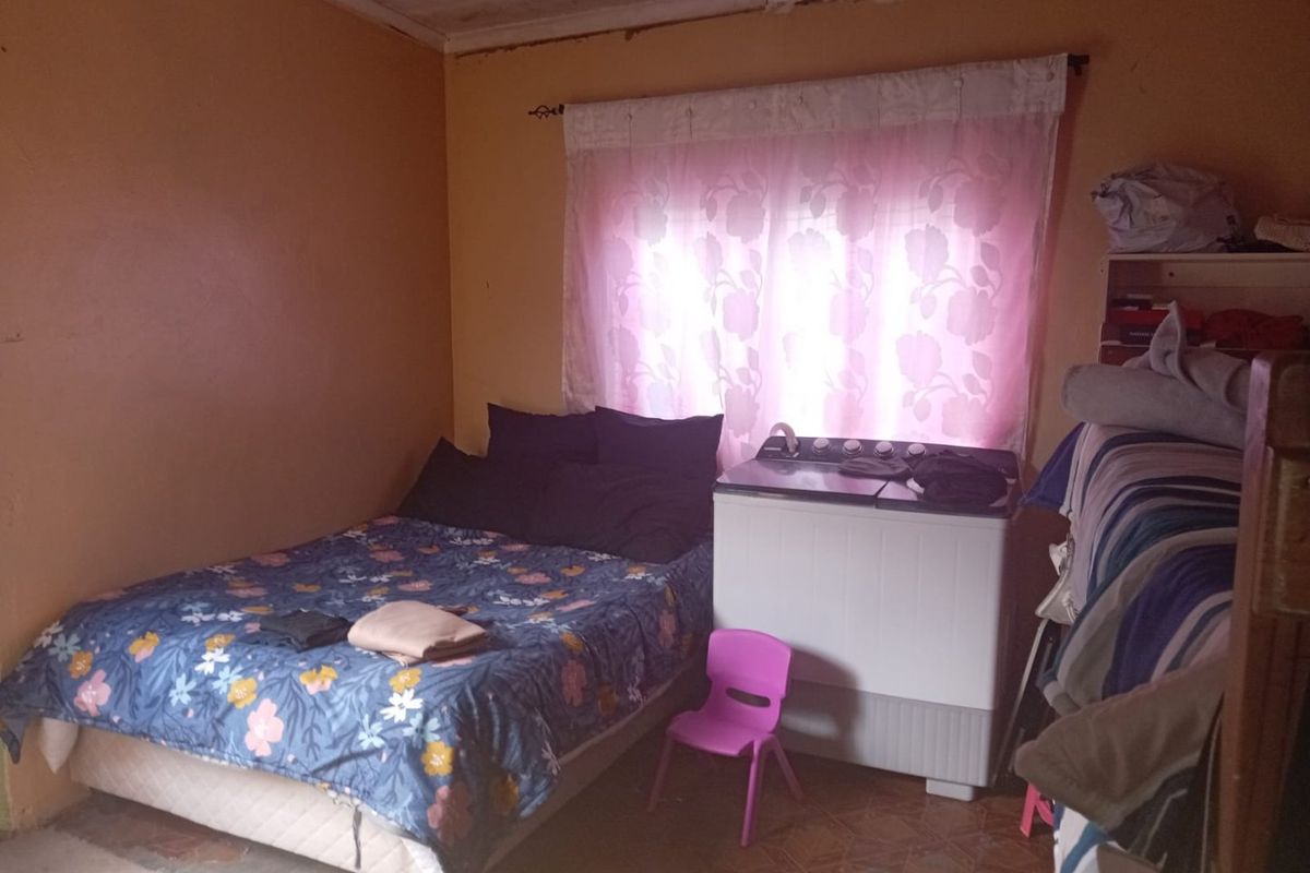 A bedroom space featuring dated wall finishes and visible ceiling damage, requiring maintenance and cosmetic updates to improve the overall condition.
