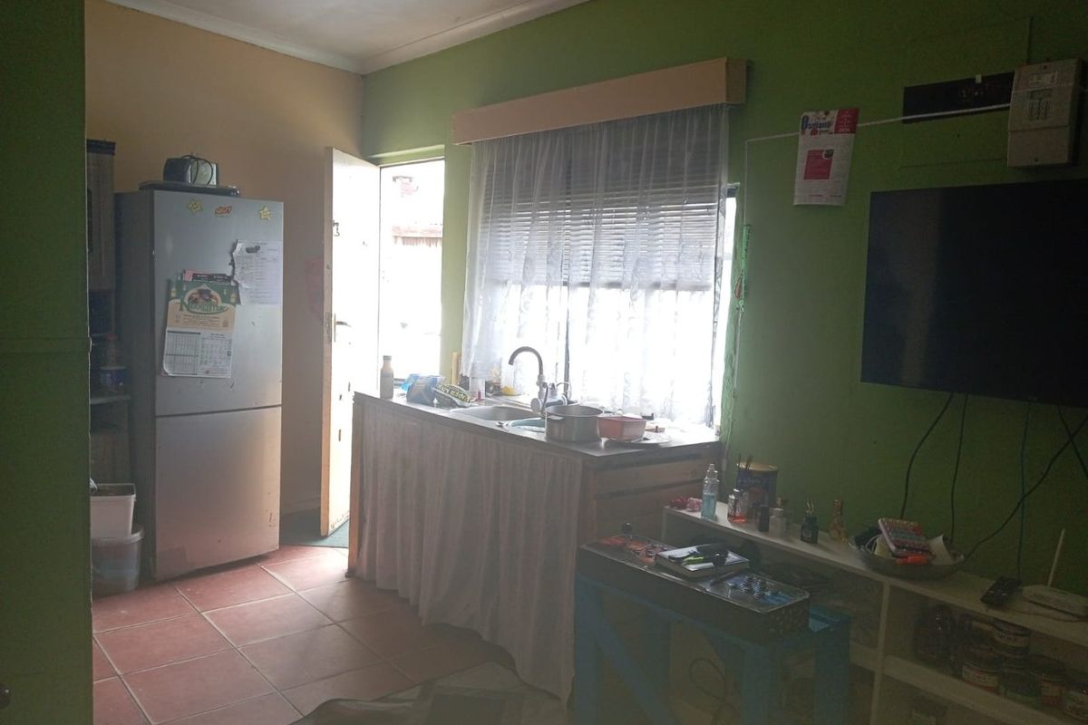 A compact kitchen area featuring tiled flooring, a stainless steel sink, and direct access to an exterior door.