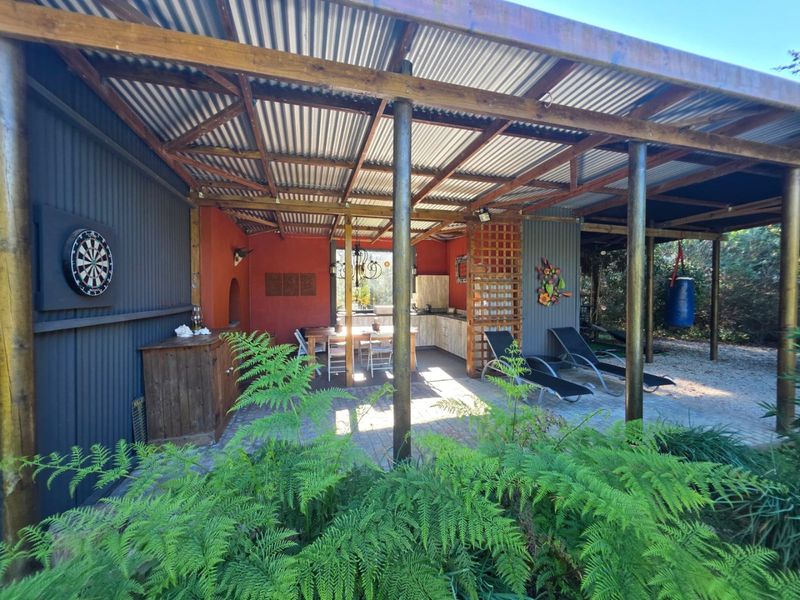 Covered outdoor patio area featuring a rustic corrugated iron roof, timber structure, and a built-in kitchenette, ideal for outdoor entertaining.