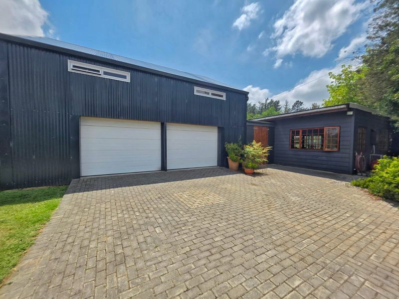 A well-maintained double garage featuring modern corrugated metal cladding and a spacious paved driveway area.