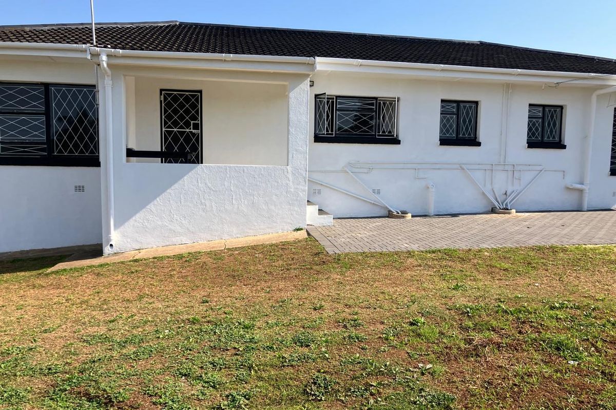 Rear view of the house featuring a paved patio area, security gates, and security bars on the windows.