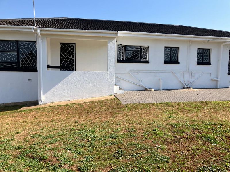 Rear view of the house featuring a paved patio area, security gates, and security bars on the windows.
