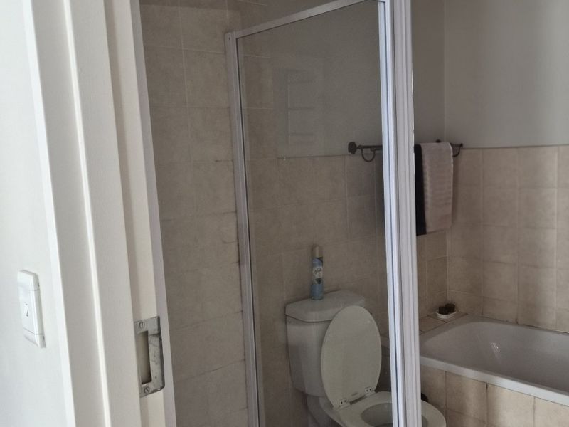 A functional bathroom featuring a separate shower enclosure, a standard toilet, and a built-in bathtub with neutral wall and floor tiling.