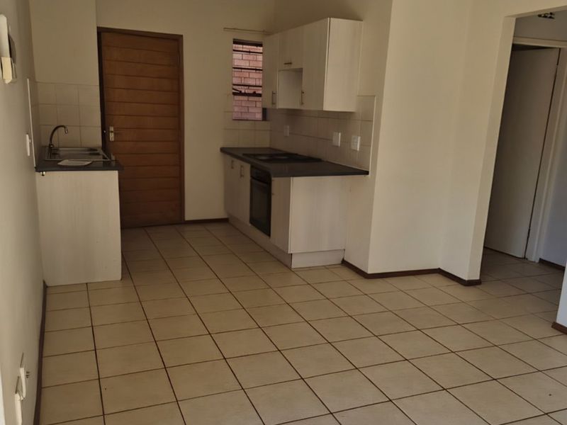 An empty kitchen featuring built-in cabinetry, a built-in oven, hob, and ceramic tiled flooring, offering a functional space ready for personalization.