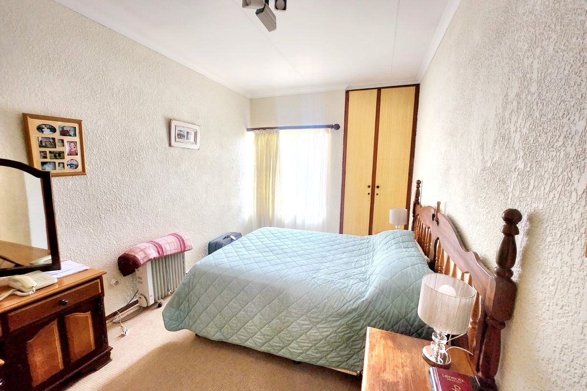 A bedroom featuring textured walls, a built-in wardrobe, and a wall-mounted radiator, offering a functional space with potential for modernization.