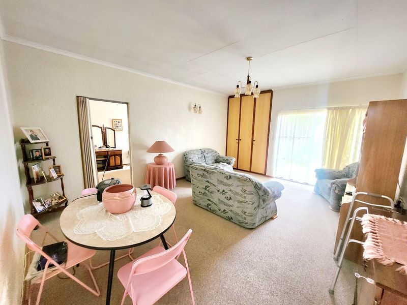 A living room featuring carpeted flooring, a built-in cupboard, and a sliding glass door providing access to the exterior.