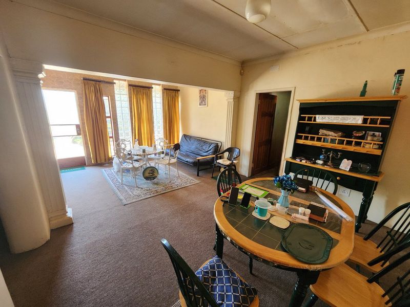 Open plan living and dining area featuring decorative columns, glass block windows, and carpet flooring.