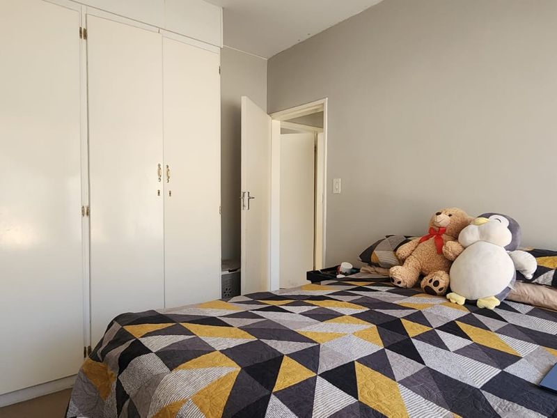 A functional bedroom featuring ample built-in cupboard storage and neutral wall finishes, providing a practical space for rest.