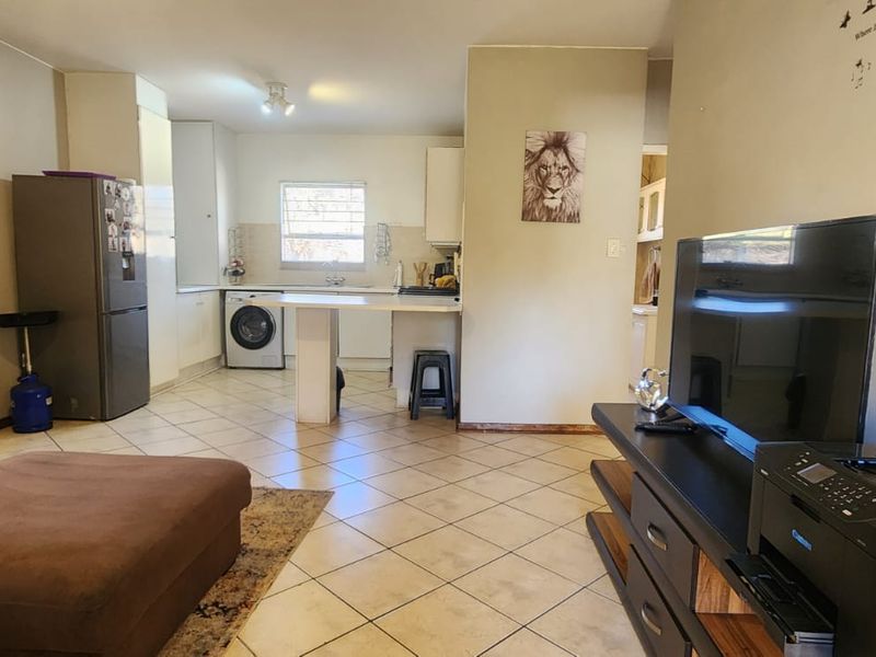 Open-plan living area featuring tiled flooring and a functional kitchen space with built-in cabinetry and a breakfast bar.