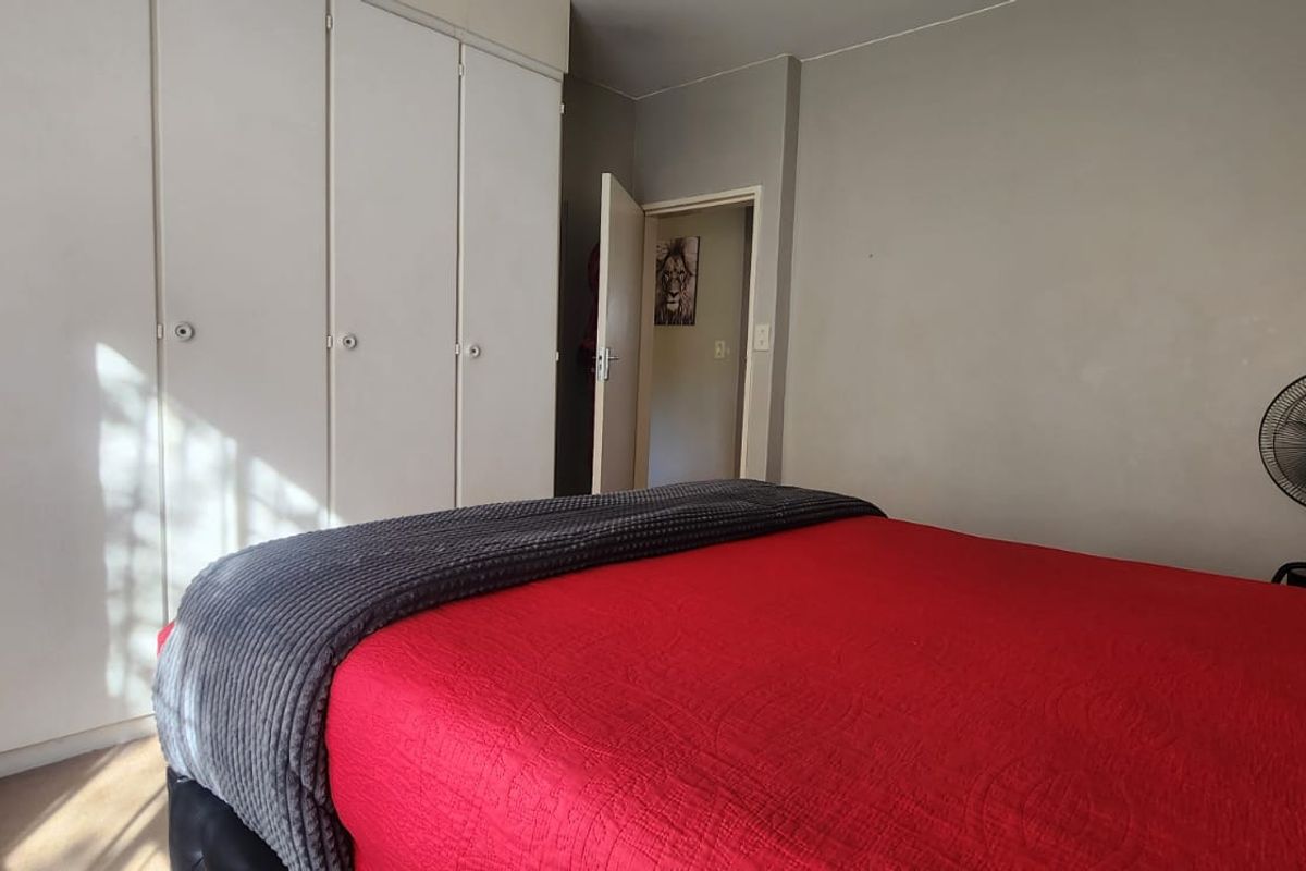A bedroom featuring built-in cupboards and neutral wall finishes, providing a functional space with ample storage.