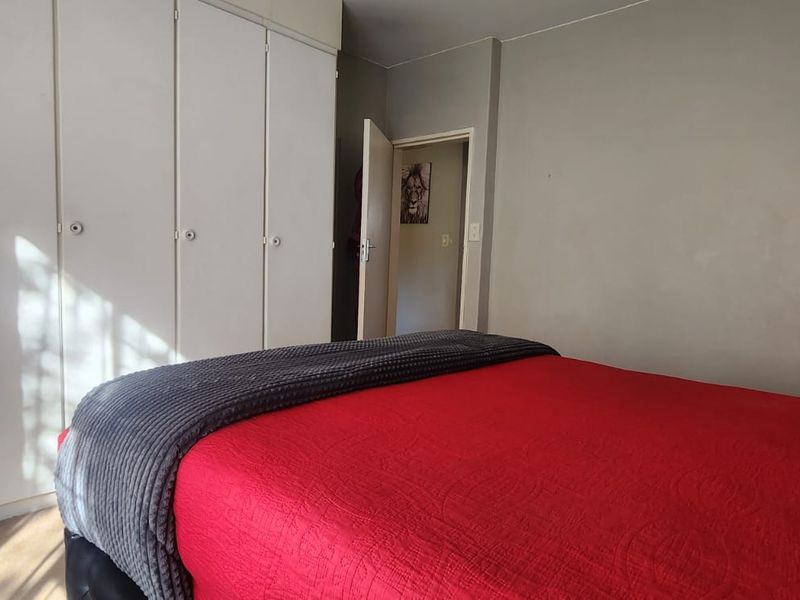 A bedroom featuring built-in cupboards and neutral wall finishes, providing a functional space with ample storage.