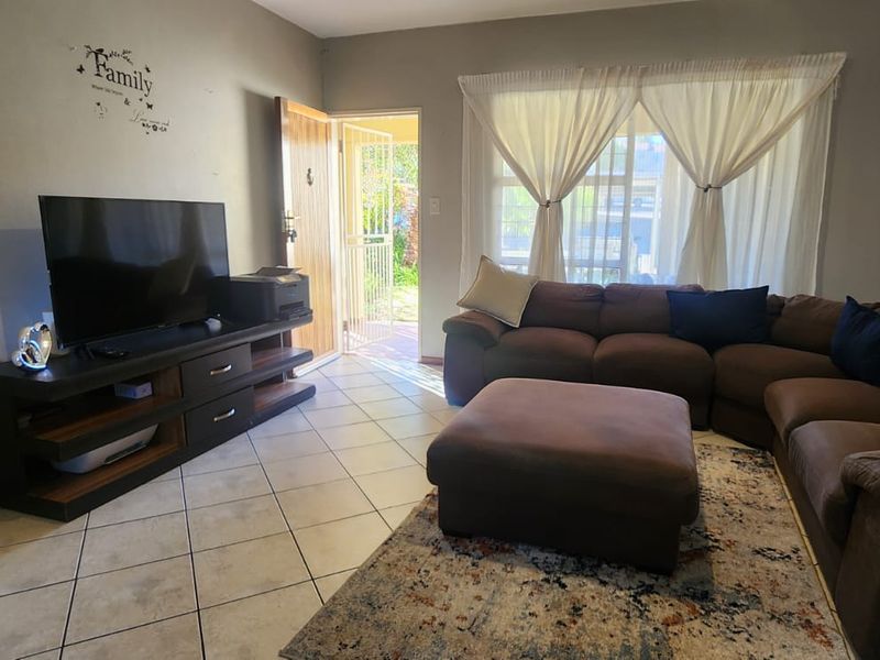 A living room featuring tiled flooring and direct access to the exterior through a security gate and door.