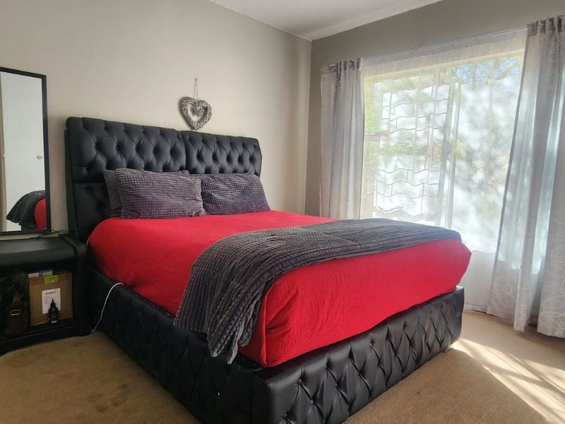 A well-lit bedroom featuring carpeted flooring and a large window, providing a comfortable and functional living space.
