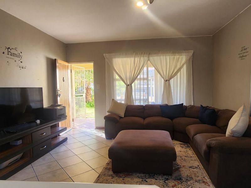 A functional living room featuring ceramic floor tiles and direct access to the exterior through a security gate and sliding door.