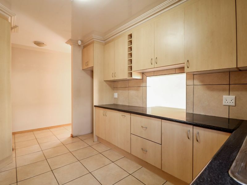 A functional kitchen featuring light wood-tone cabinetry, dark granite countertops, and neutral ceramic floor tiles, offering a clean and practical workspace.