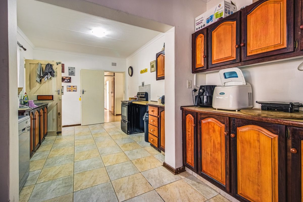A functional kitchen featuring traditional wooden cabinetry, tiled flooring, and a freestanding stove, offering potential for a modern renovation.