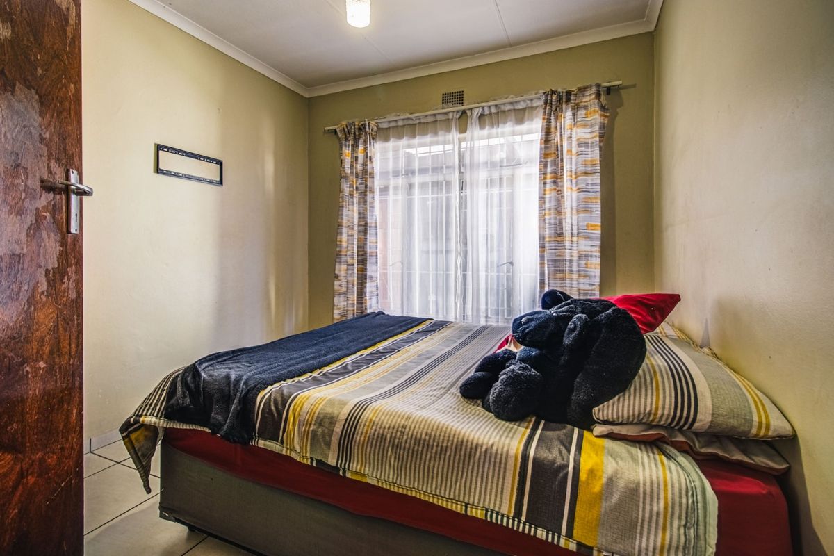A compact bedroom featuring tiled flooring and a window with curtain rails, requiring minor cosmetic updates to refresh the space.