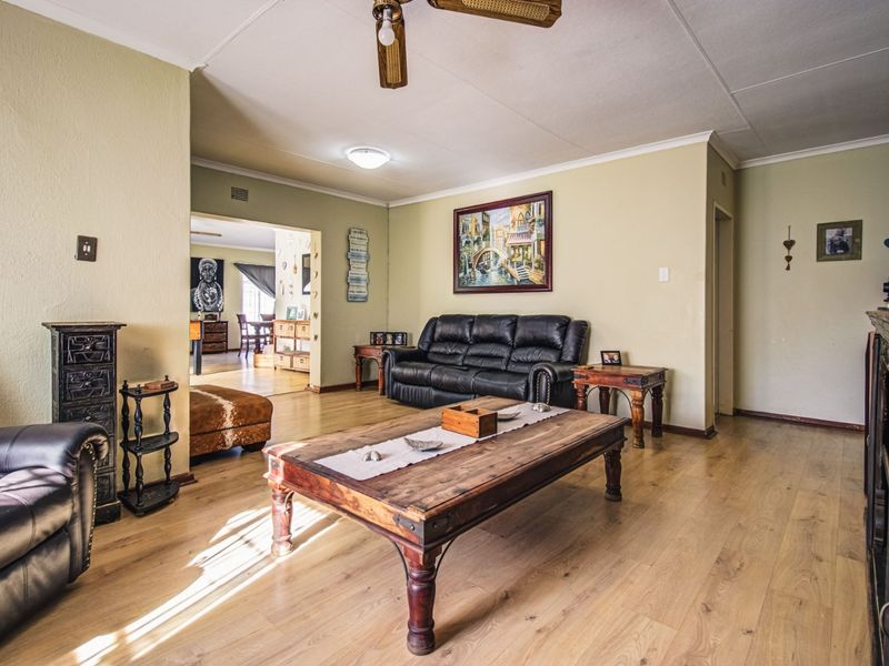 Spacious living room featuring light-toned laminate flooring and a ceiling fan, with an open-plan flow leading into the adjacent dining area.