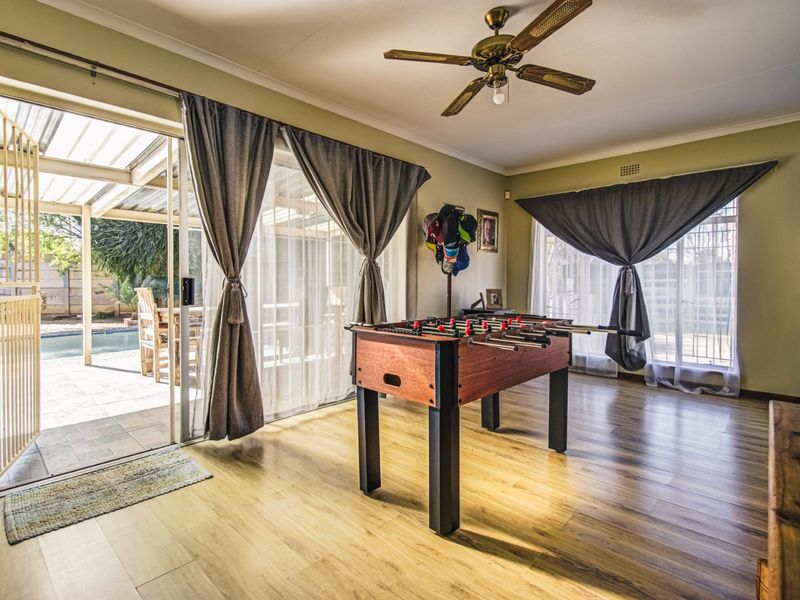 Spacious living area featuring laminate flooring, a ceiling fan, and large sliding glass doors providing direct access to the outdoor patio and pool area.