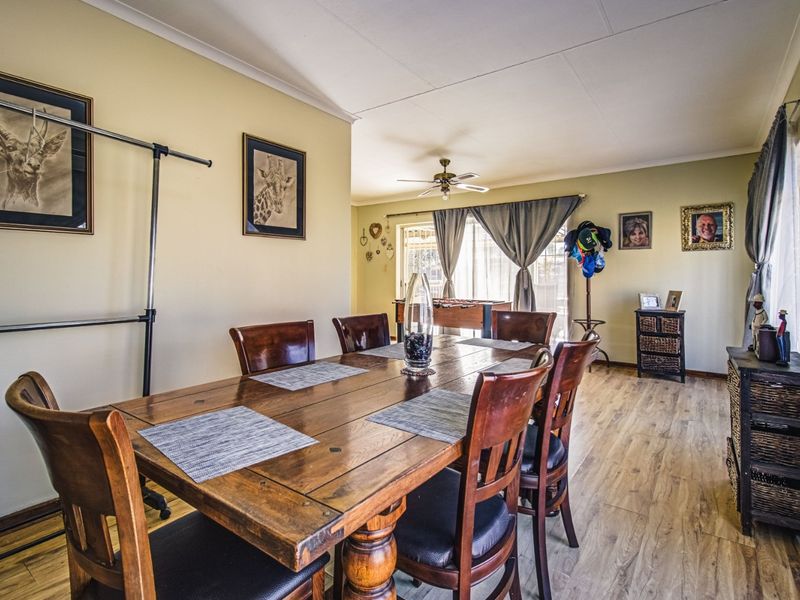A dining room featuring laminate flooring, a ceiling fan, and sliding glass doors leading to an outdoor area.