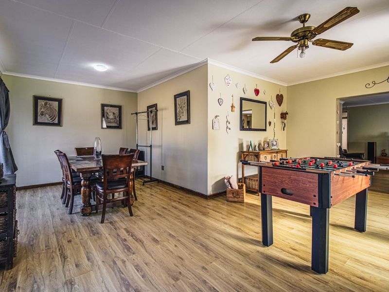 Spacious living and dining area featuring durable laminate flooring, a ceiling fan, and neutral wall tones, offering a versatile layout for family living.