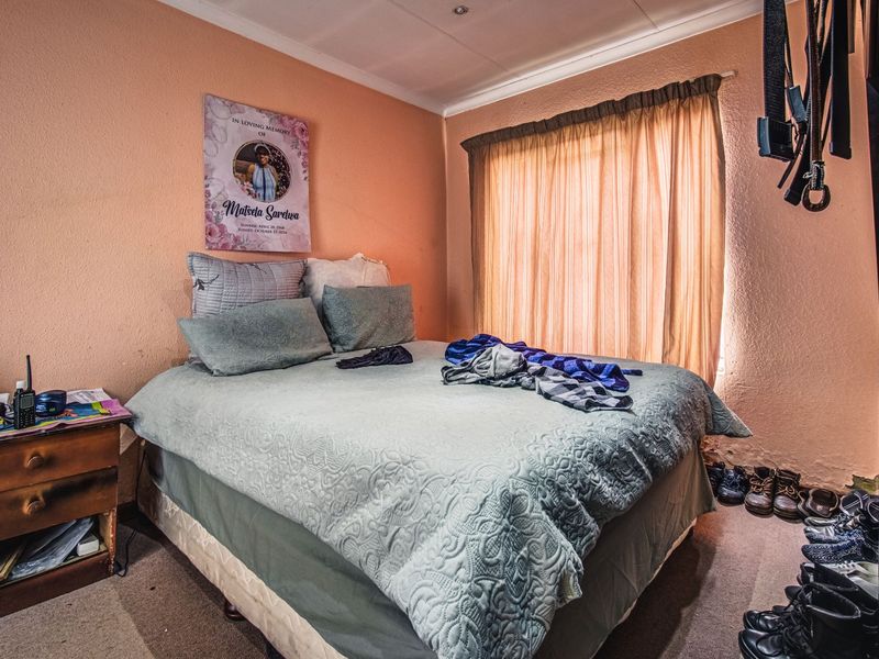 A bedroom featuring peach-toned walls, recessed ceiling lighting, and a window with curtain rails, requiring cosmetic updates to improve the overall finish.