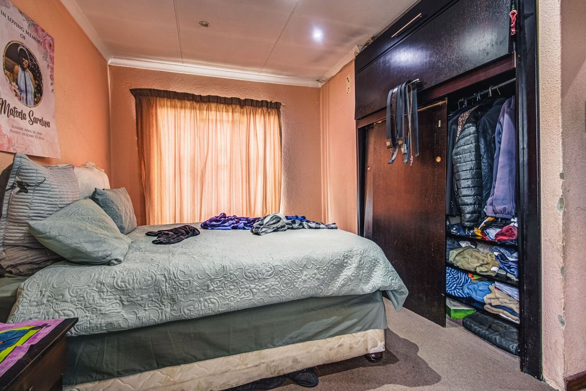 A bedroom featuring a built-in wardrobe with dark wood finish, recessed lighting, and cove cornicing, requiring cosmetic updates to the wall finishes.