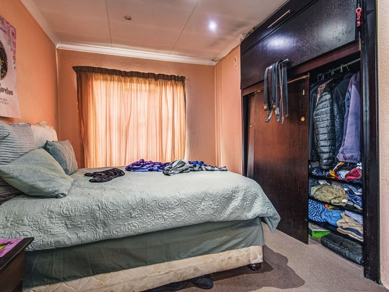 A bedroom featuring a built-in wardrobe with dark wood finish, recessed lighting, and cove cornicing, requiring cosmetic updates to the wall finishes.