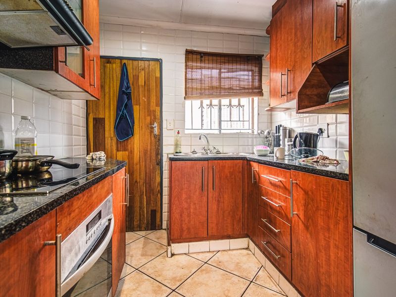 A functional kitchen featuring wooden cabinetry, granite countertops, a built-in oven, and a tiled backsplash, offering a classic layout with practical storage space.