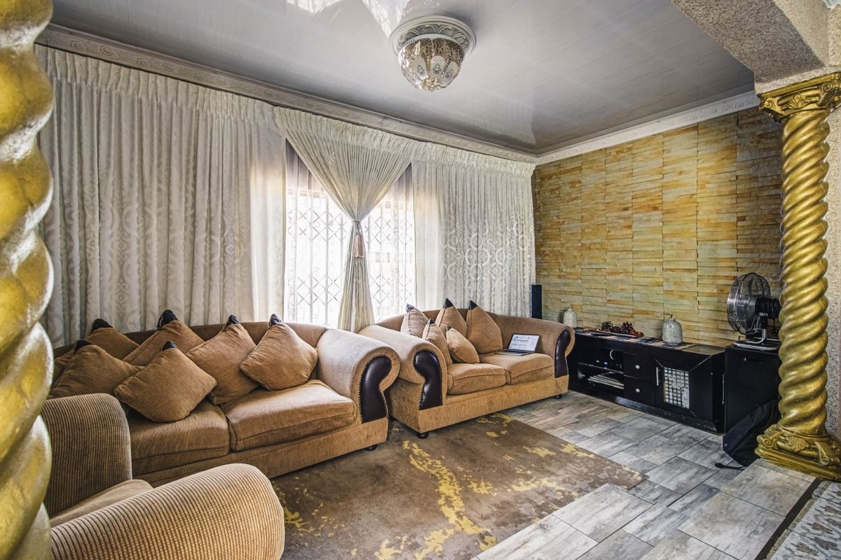 A living room featuring a stone-clad accent wall, decorative columns, and tiled flooring, offering a distinct architectural style.