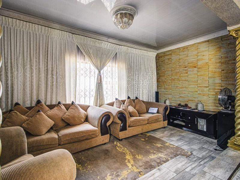 A living room featuring a stone-clad accent wall, decorative columns, and tiled flooring, offering a distinct architectural style.